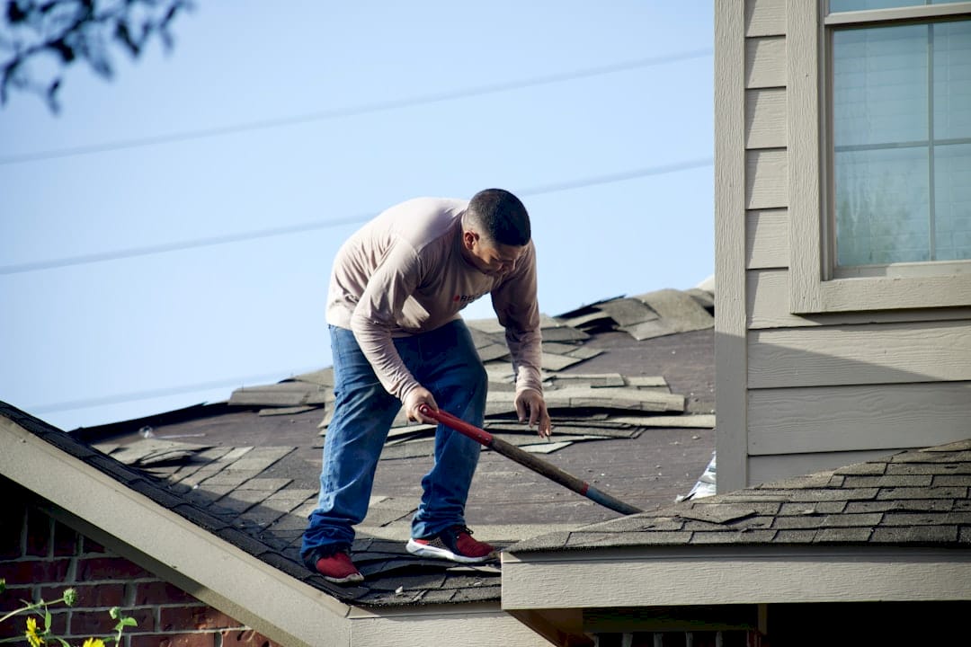 Homeowner inspecting roof with binoculars outdoors